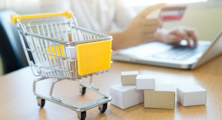 Miniatyr kundvagn och dator som symboliserar e-handel